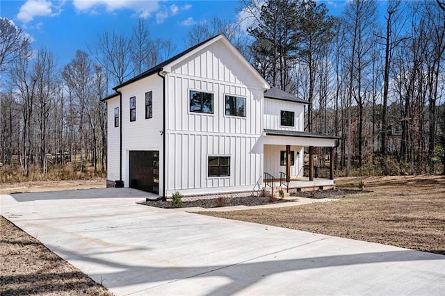 modern farmhouse with driveway, an attached garage, a porch, and board and batten siding