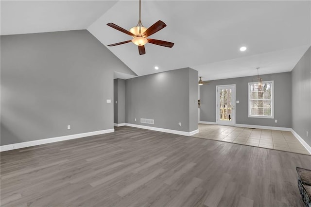 unfurnished living room featuring visible vents, baseboards, lofted ceiling, ceiling fan with notable chandelier, and wood finished floors