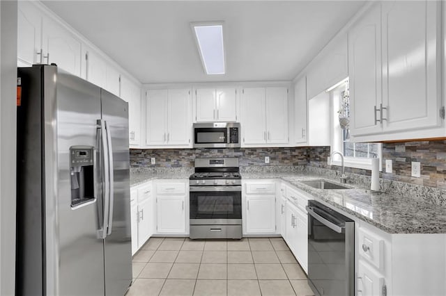 kitchen with light tile patterned floors, backsplash, stainless steel appliances, and a sink