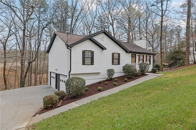 view of front of home featuring a front lawn, a chimney, concrete driveway, and an attached garage