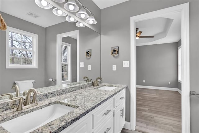 bathroom with visible vents, a sink, wood finished floors, baseboards, and ceiling fan