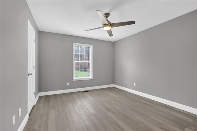 spare room with wood finished floors, visible vents, and baseboards