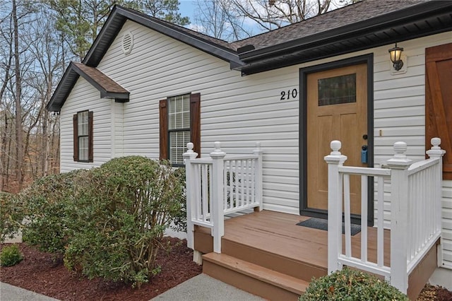 doorway to property with roof with shingles