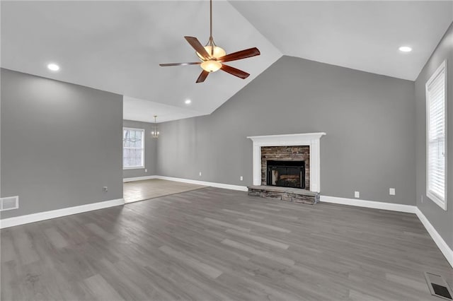 unfurnished living room with visible vents, baseboards, a stone fireplace, wood finished floors, and a ceiling fan