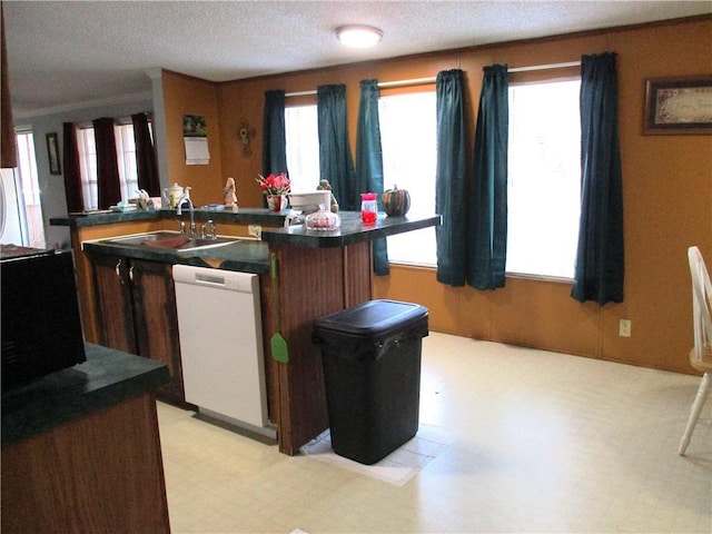 kitchen with sink, dishwasher, a kitchen island with sink, and a textured ceiling