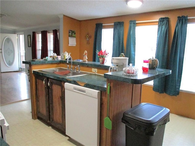 kitchen featuring dishwasher, sink, a center island with sink, and a textured ceiling