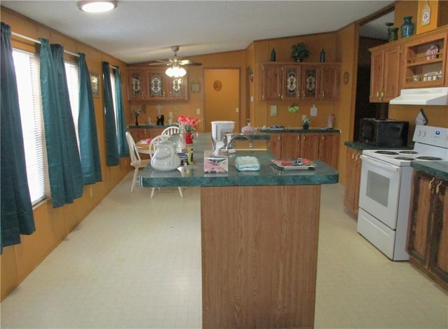 kitchen featuring ceiling fan, sink, a kitchen island with sink, and electric range