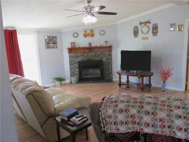 living room with ornamental molding, a stone fireplace, hardwood / wood-style floors, and ceiling fan