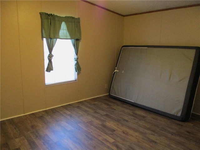 empty room with crown molding and dark hardwood / wood-style floors