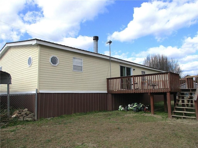 rear view of house with a wooden deck and a lawn