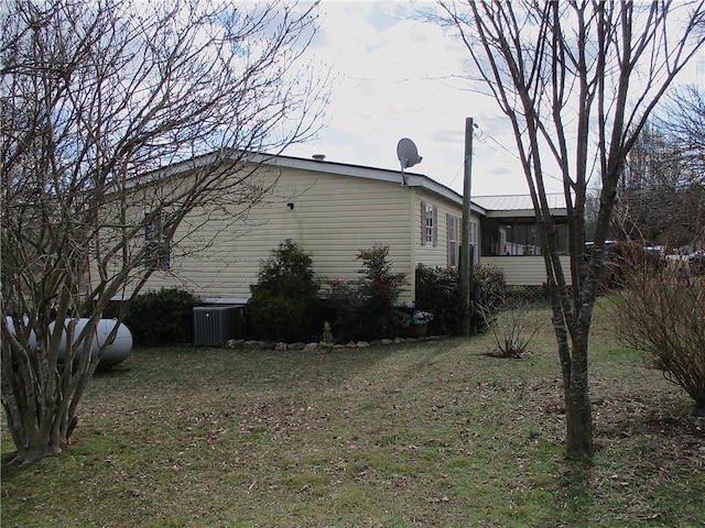 view of property exterior with a sunroom, cooling unit, and a lawn