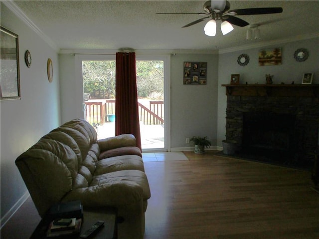 living room featuring ceiling fan, a fireplace, ornamental molding, and a textured ceiling