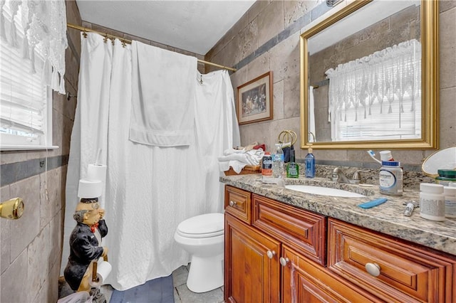 bathroom with tile walls, vanity, a shower with curtain, and toilet