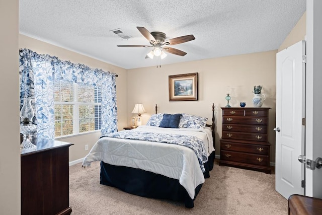 bedroom featuring ceiling fan, light colored carpet, and a textured ceiling