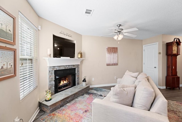 living room featuring ceiling fan, a fireplace, and dark hardwood / wood-style floors