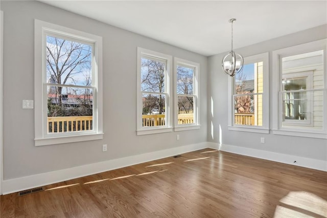 unfurnished dining area featuring dark hardwood / wood-style floors, plenty of natural light, and a notable chandelier