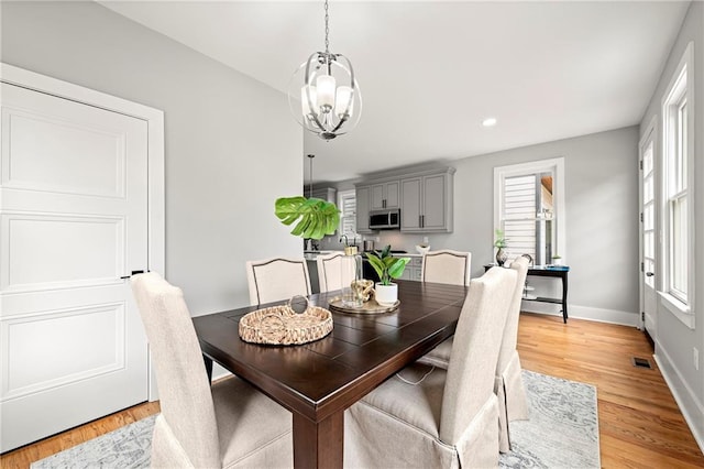 dining room with a notable chandelier, a healthy amount of sunlight, and light hardwood / wood-style floors