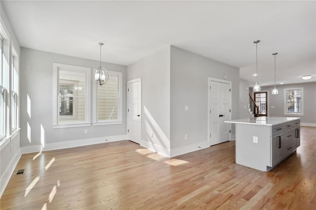 kitchen featuring light hardwood / wood-style flooring, a kitchen island, hanging light fixtures, and a chandelier