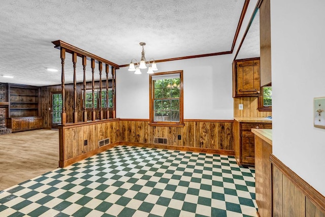 2775 Doaks Run Ct, Tucker, GA 30084 - unfurnished dining area featuring a textured ceiling, a chandelier, wooden walls, a wainscoted wall, and built in shelves