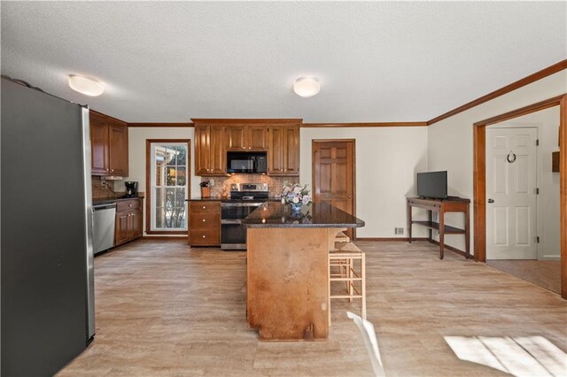 kitchen featuring stainless steel appliances, a center island, light hardwood / wood-style floors, backsplash, and a breakfast bar