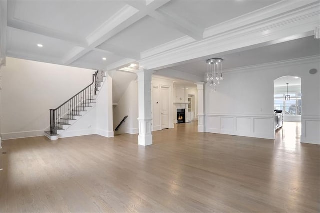 unfurnished living room featuring beam ceiling, a lit fireplace, and wood finished floors