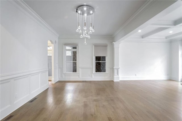 unfurnished living room featuring visible vents, beam ceiling, wood finished floors, a notable chandelier, and ornate columns