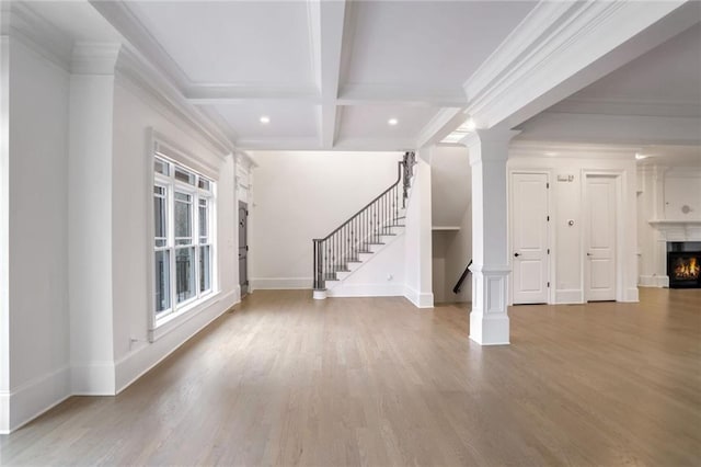 unfurnished living room with stairway, a lit fireplace, beam ceiling, wood finished floors, and coffered ceiling