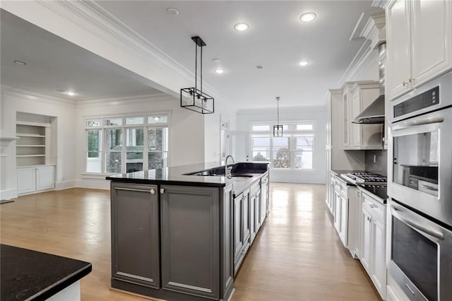 kitchen featuring dark countertops, light wood-style floors, a kitchen island with sink, and stainless steel appliances