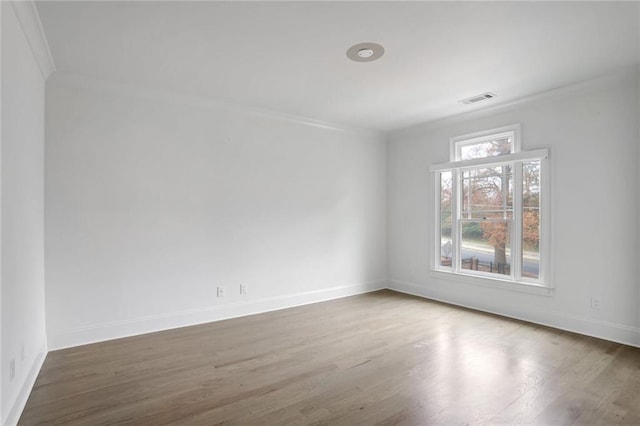 unfurnished room with visible vents, ornamental molding, baseboards, and wood finished floors