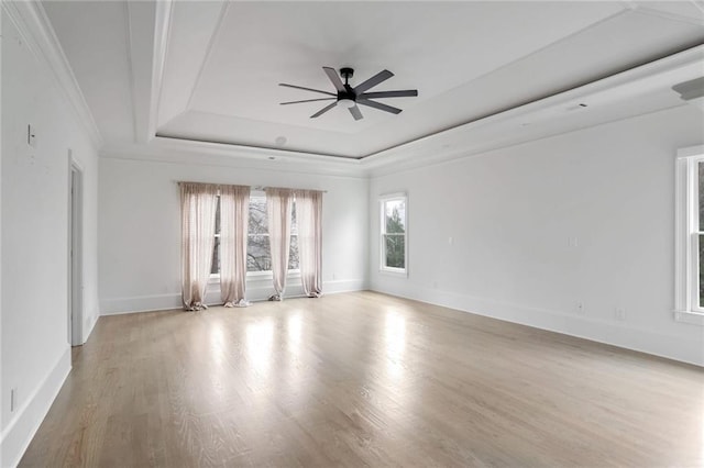 unfurnished room featuring wood finished floors, baseboards, a tray ceiling, ornamental molding, and ceiling fan