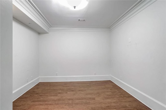 unfurnished room featuring visible vents, crown molding, baseboards, and wood finished floors