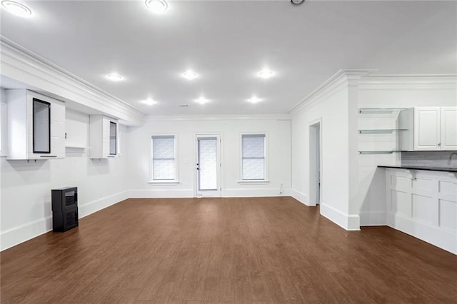 unfurnished living room featuring crown molding, baseboards, and dark wood-style flooring