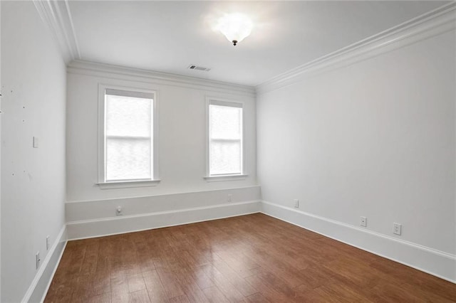 unfurnished room featuring visible vents, dark wood-style flooring, baseboards, and ornamental molding