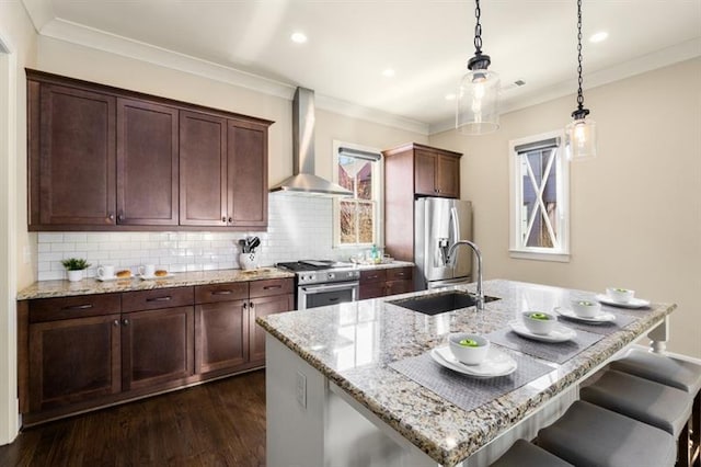 kitchen with dark wood finished floors, wall chimney exhaust hood, appliances with stainless steel finishes, ornamental molding, and a sink