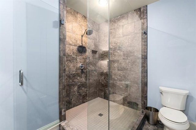 full bathroom with toilet, a stall shower, and baseboards