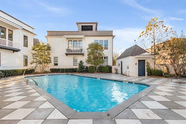 community pool with an outbuilding, a patio area, and fence