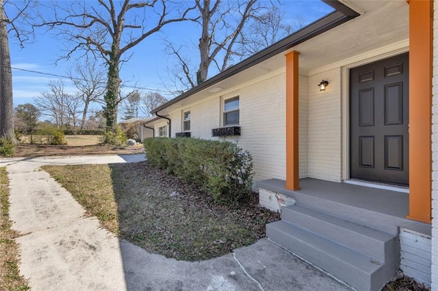 property entrance with covered porch and brick siding