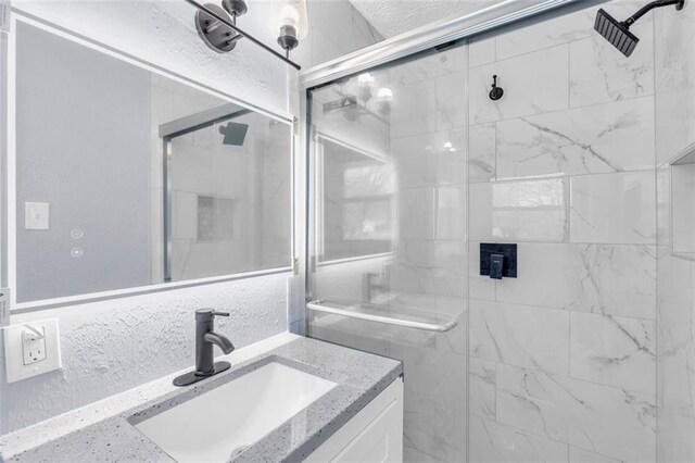 full bathroom with a stall shower, vanity, and a textured wall