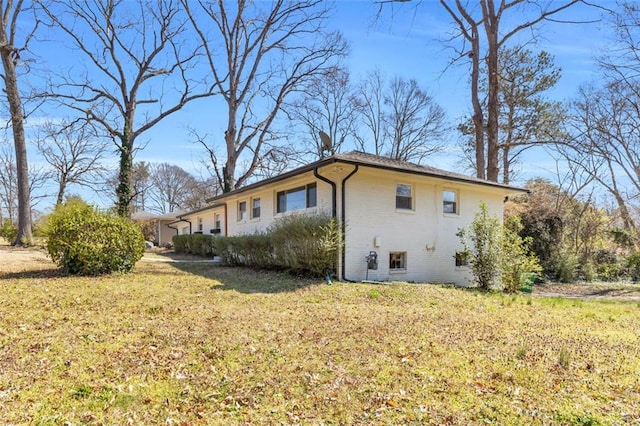 view of side of property featuring brick siding and a yard