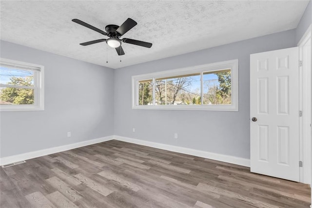 unfurnished bedroom featuring visible vents, wood finished floors, baseboards, and a textured ceiling