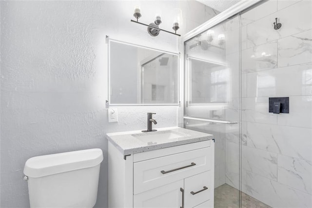 full bath with vanity, a shower stall, toilet, and a textured wall