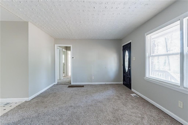 carpeted empty room with a textured ceiling