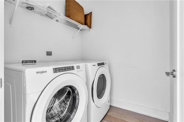 clothes washing area featuring washing machine and dryer and wood-type flooring