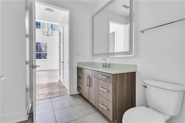 bathroom with tile patterned flooring, vanity, a chandelier, and toilet