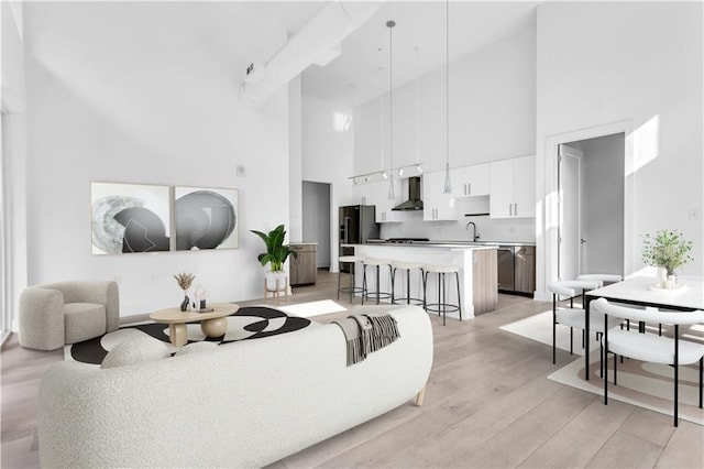 living room featuring a high ceiling, light wood-type flooring, and sink