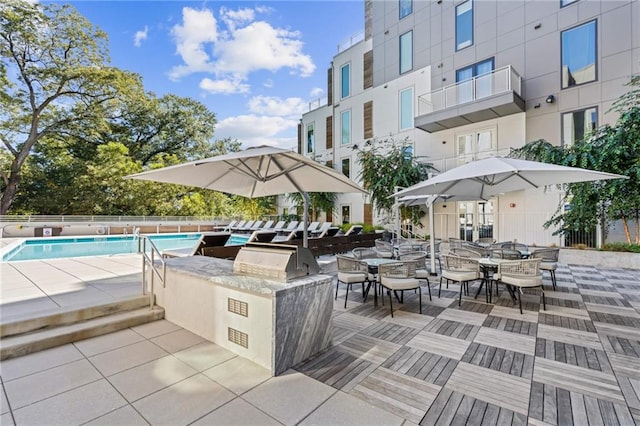 view of patio with a grill, a community pool, and exterior kitchen