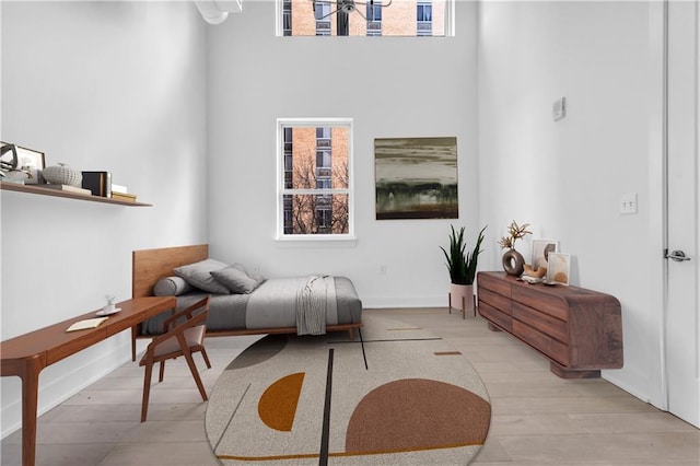 bedroom with light hardwood / wood-style floors and a high ceiling