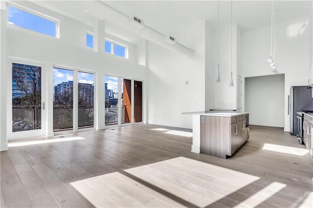 unfurnished living room featuring light wood-type flooring and a towering ceiling