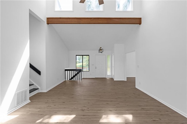 unfurnished living room with hardwood / wood-style flooring, high vaulted ceiling, and ceiling fan