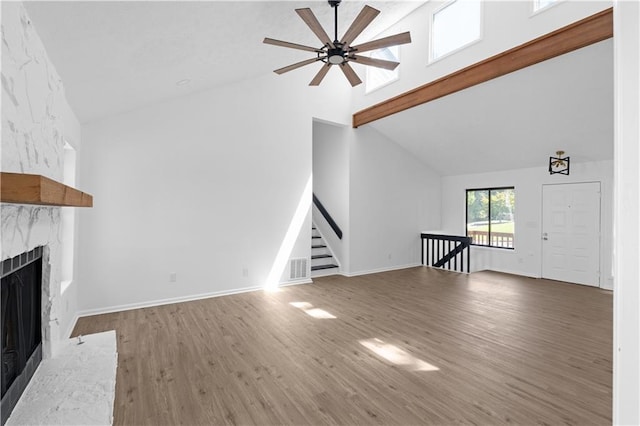 unfurnished living room featuring high vaulted ceiling, a fireplace, hardwood / wood-style floors, and beamed ceiling